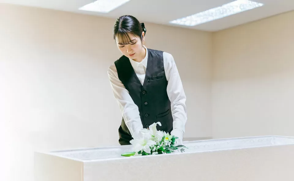祭壇に白い花を供える女性の葬儀スタッフ